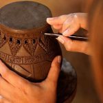 Hands make potter inflicts a decorative pattern on earthenware